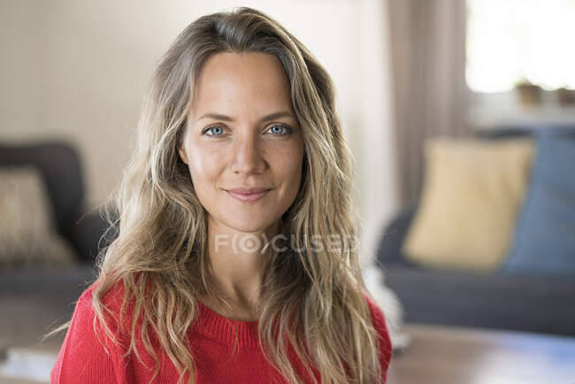 Retrato de una mujer rubia sonriente en casa - foto de stock