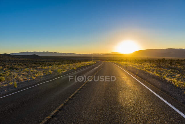USA, Nevada, Lange kurvenreiche Straße bei Sonnenuntergang — Stockfoto