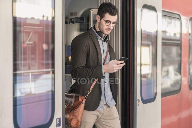 Hombre joven usando el teléfono celular en tren de cercanías - foto de stock