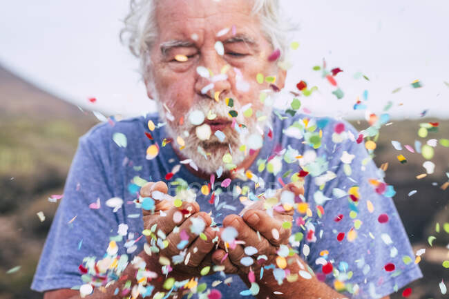Senior homme souffler des confettis en plein air — Photo de stock