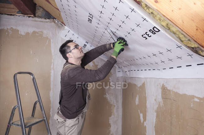 Roof insulation, worker fixing sarking membrane — Stock Photo