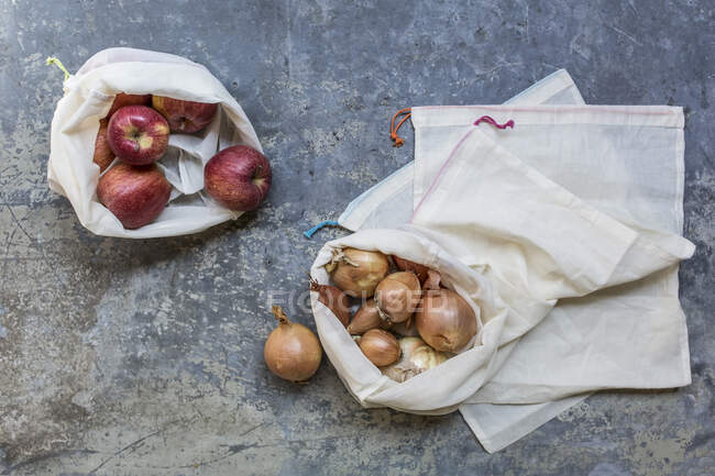 Zwiebeln und Äpfel in Stofftaschen zur Abfallvermeidung — Stockfoto