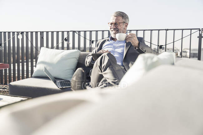 Lächelnder Geschäftsmann mit Tasse Kaffee und Tablet auf Dachterrasse — Stockfoto