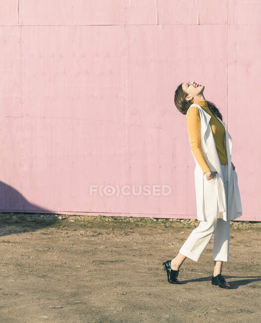 Felice giovane donna in piedi davanti al muro rosa — Foto stock