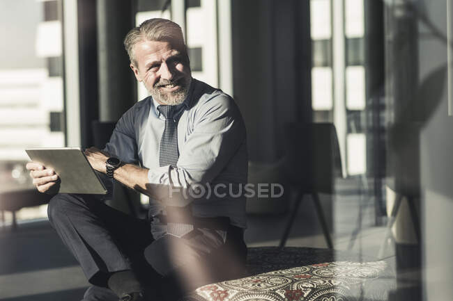 Посмішка дорослого бізнесмена, який використовує планшет в офісі. — стокове фото