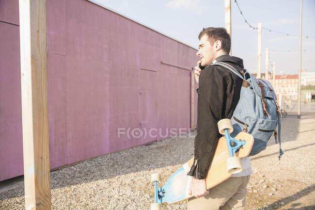 Young man with skatebaord and cell phone on the move in the city — Stock Photo