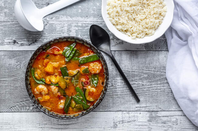 Red curry with sweet potato, yellow and red bell pepper, zucchini, sugar pea, shrimps and rice — Stock Photo