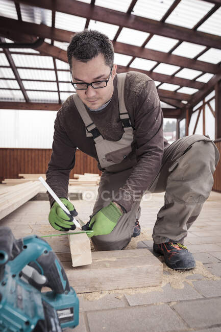 Roof insulation, worker sawing woodbar — Stock Photo