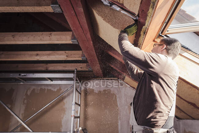 Roof insulation, worker filling pitched roof with wood fibre insulation — Stock Photo