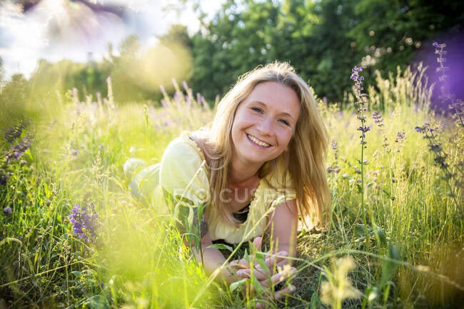 Ritratto di donna bionda felice sdraiata sul prato fiorito in estate — Foto stock