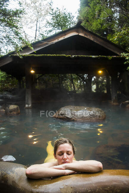 Japón, Kyushu, mujer disfrutando de las aguas termales - foto de stock