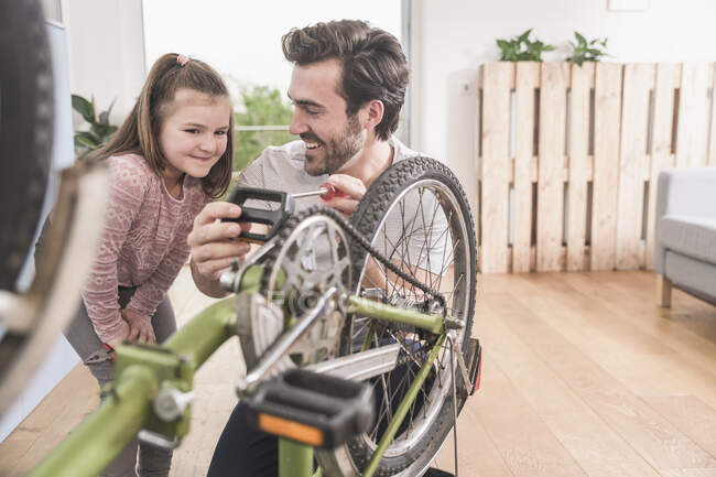 Jeune homme et petite fille réparer vélo ensemble — Photo de stock