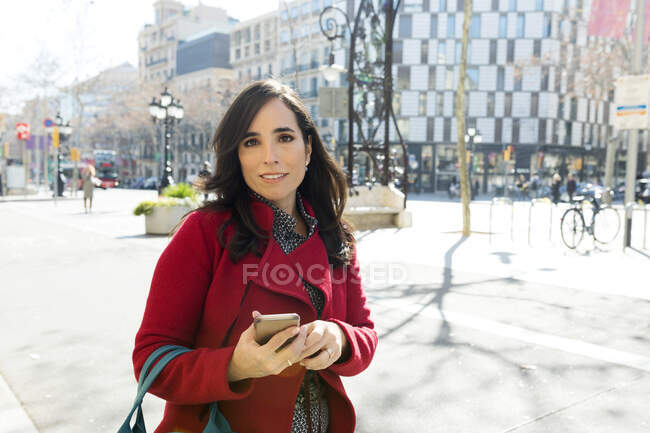 Portrait of woman with cell phone in the city — Stock Photo