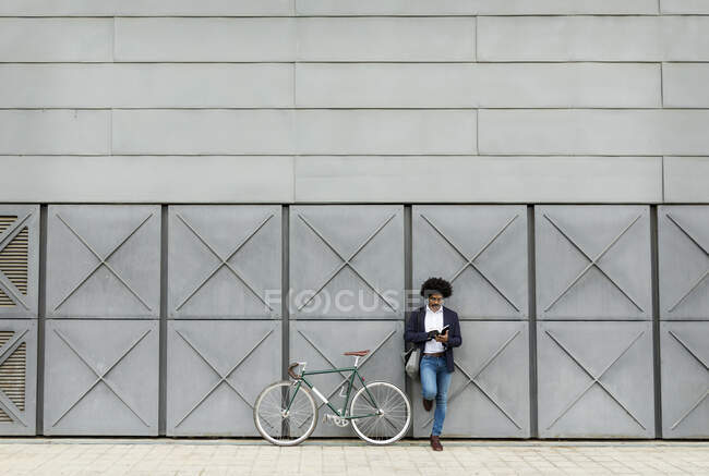 Geschäftsmann mit Fahrrad lehnt an einer Lesewand — Stockfoto