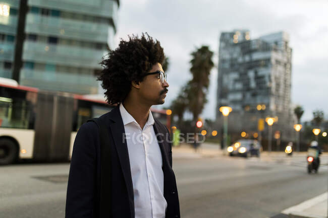 Испания, Барселона, бизнесмен стоит на одной из улиц города в сумерках — стоковое фото