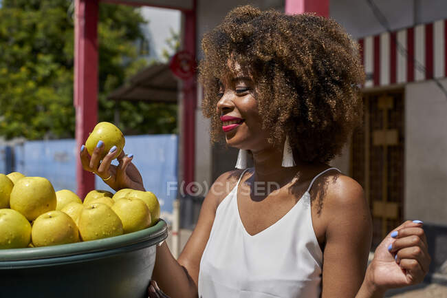 Sonriente joven mujer elegir manzanas al aire libre - foto de stock
