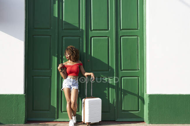 Donna in rosso con una valigia e un telefono — Foto stock