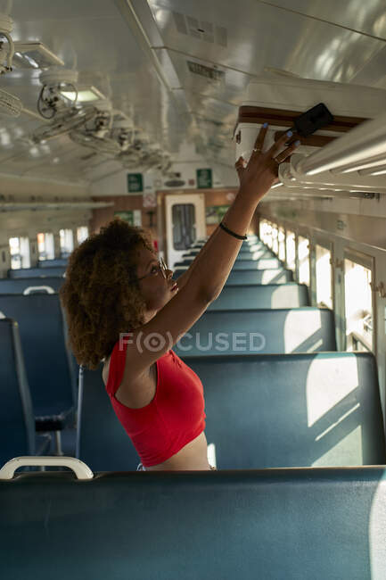 Mujer joven colocando su maleta en un tren - foto de stock