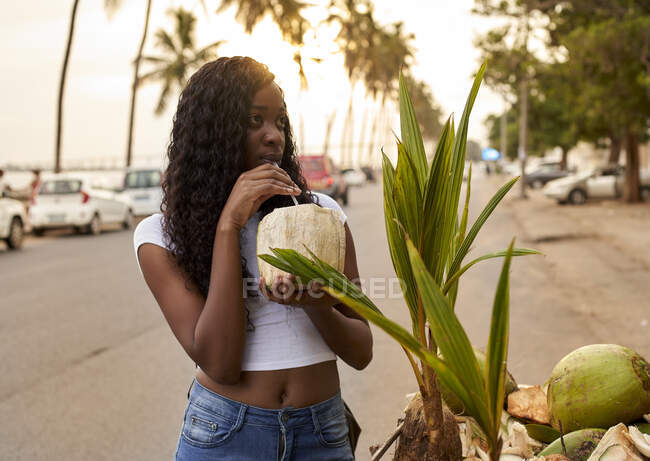 Mocambique, Maputo, portrait of  young woman drinking coconut water on the street — Stock Photo