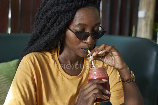 Giovane donna con dreadlocks bere un frullato in un caffè — Foto stock