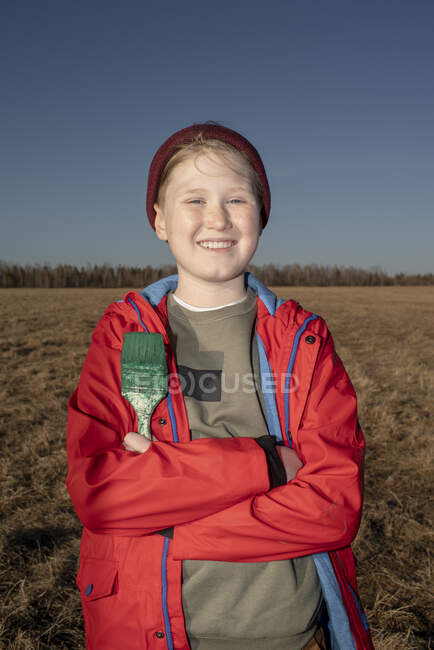 Retrato de menino sorridente segurando pincel de pintura na paisagem estepe — Fotografia de Stock
