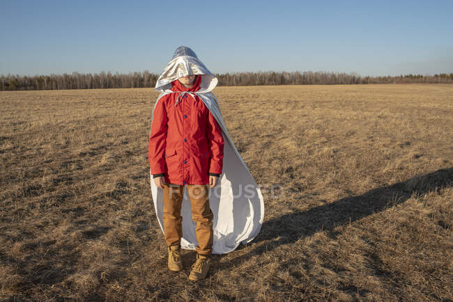 Hood of superhero costume covering boy's face in steppe landscape — Stock Photo