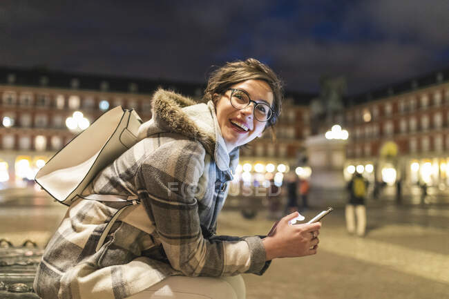 Spain, Madrid, Plaza Mayor, happy young woman using her smartphone — Stock Photo