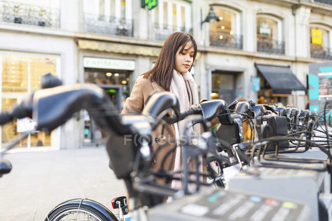 Espanha, Madrid, jovem mulher usando bicicleta alugada na cidade — Fotografia de Stock