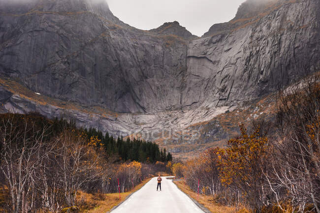 Norvège, îles Lofoten, homme debout sur une route vide entourée d'une paroi rocheuse — Photo de stock