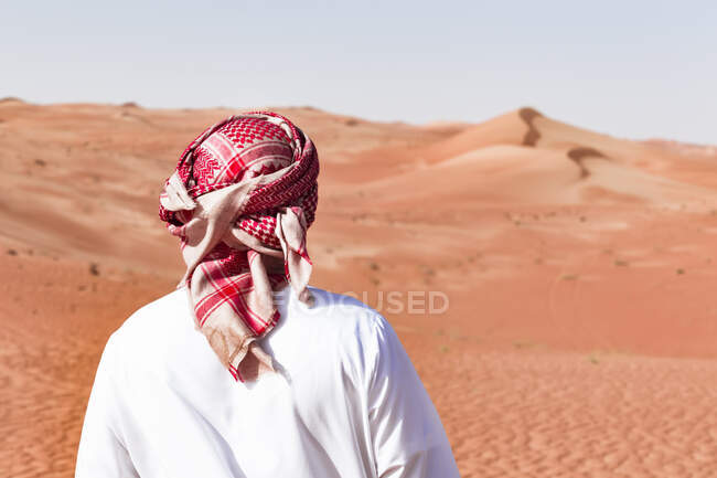 Бедуины в национальном платье, стоящие в пустыне, вид сзади, Вахиба Сэндс, Оман — стоковое фото