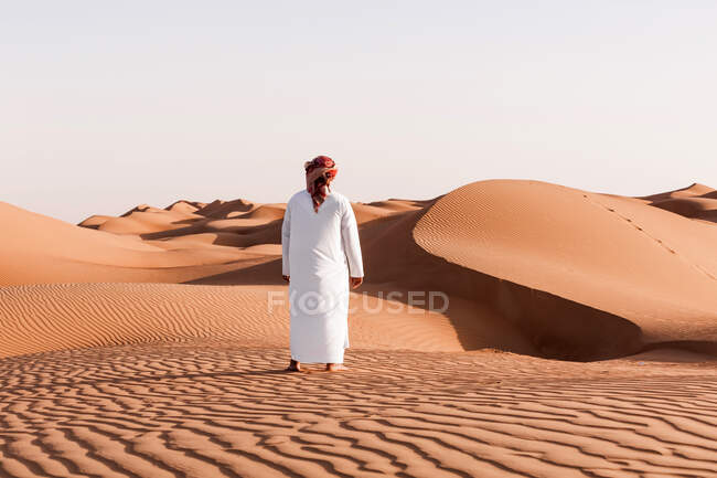 Бедуины в национальном платье, стоящие в пустыне, вид сзади, Вахиба Сэндс, Оман — стоковое фото