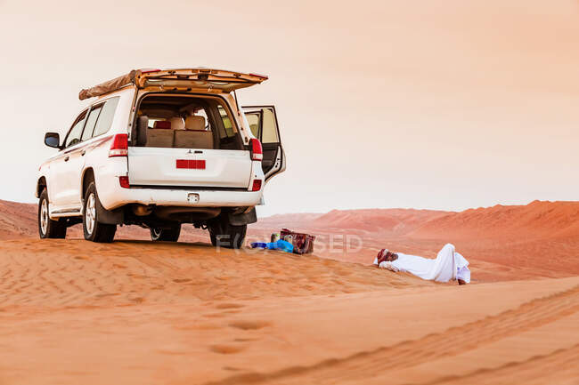 Бедуин делает перерыв рядом со своей машиной в пустыне, Вахиба Сэндс, Оман — стоковое фото