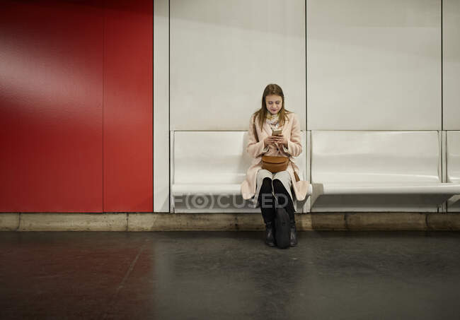 Áustria, Viena, jovem esperando na estação subterrânea usando smartphone — Fotografia de Stock