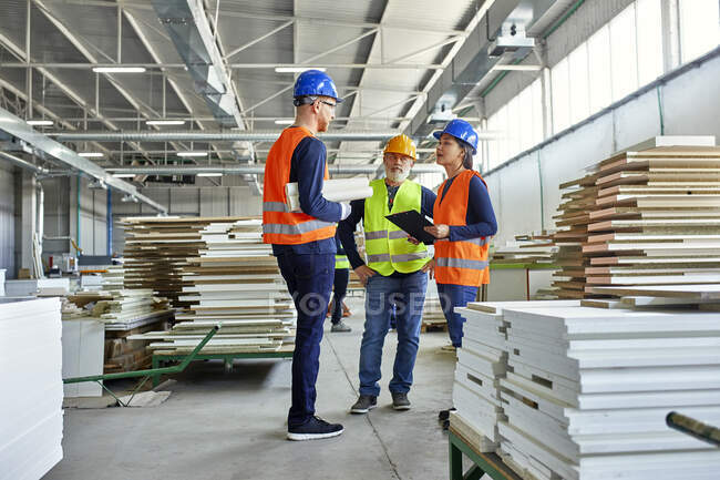 Колеги в захисному робочому одязі говорять на фабриці — стокове фото