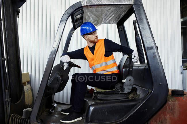 Worker on forklift in factory turning round — Stock Photo