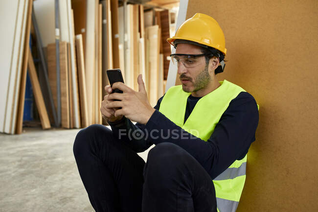 Worker using cell phone during a break in factory — Stock Photo