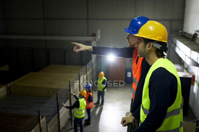 Workers instructing colleague in factory — Stock Photo