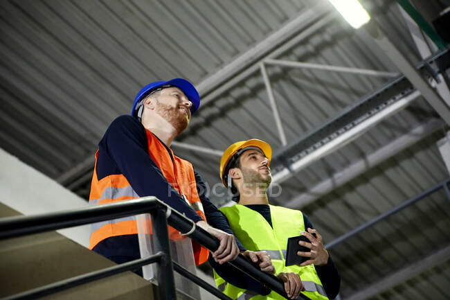 Due lavoratori in piedi al piano superiore in fabbrica — Foto stock