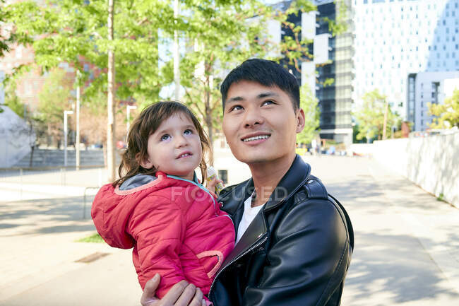 Sorridente padre tenendo piccola figlia guardando in alto — Foto stock