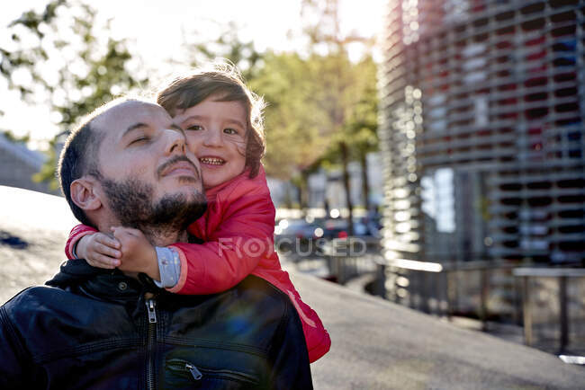 Una niña de dos años abrazando a su padre en la ciudad en invierno. Barcelona, España - foto de stock