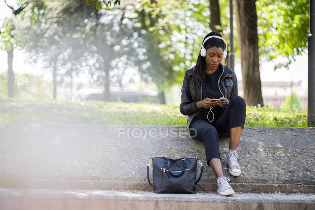 Donna che riposa nel parco urbano con cellulare e cuffie — Foto stock
