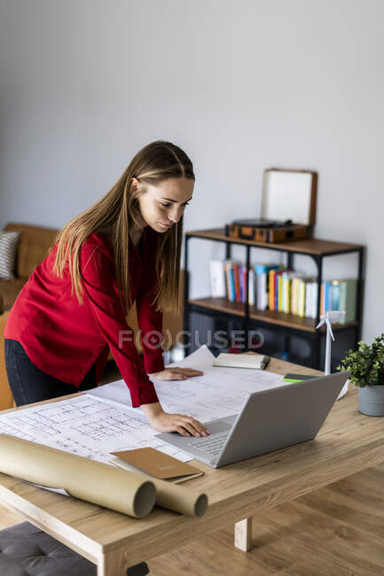 Woman in office working on plan and laptop with wind turbine model on table — Stock Photo