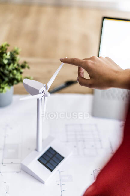 Primer plano de la mujer girando modelo de turbina eólica en la mesa - foto de stock