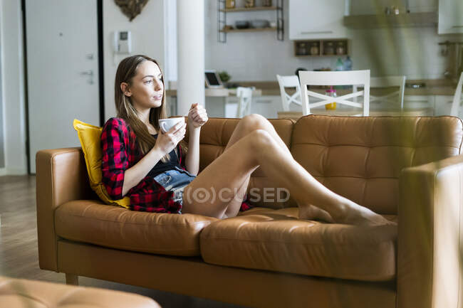 Розслаблена молода жінка їсть зернові в вітальні вдома. — стокове фото