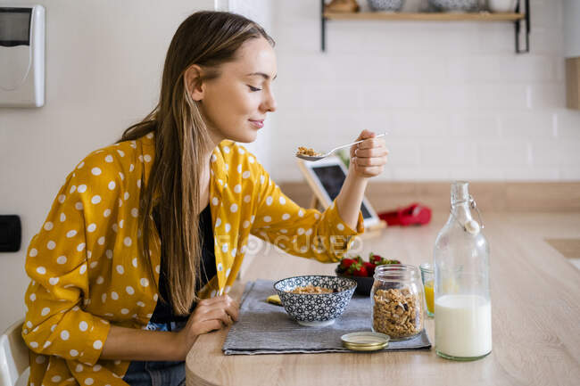 Junge Frau genießt Frühstück in Küche zu Hause — Stockfoto