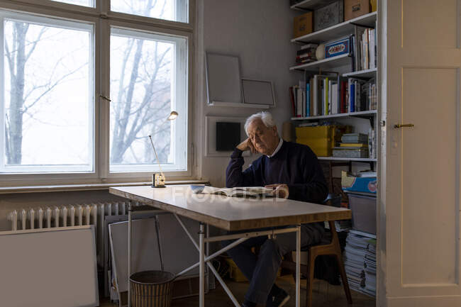 Старший чоловік читає книжку вдома. — стокове фото