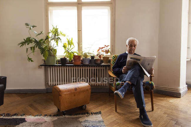 Senior man reading newspaper at home — Stock Photo