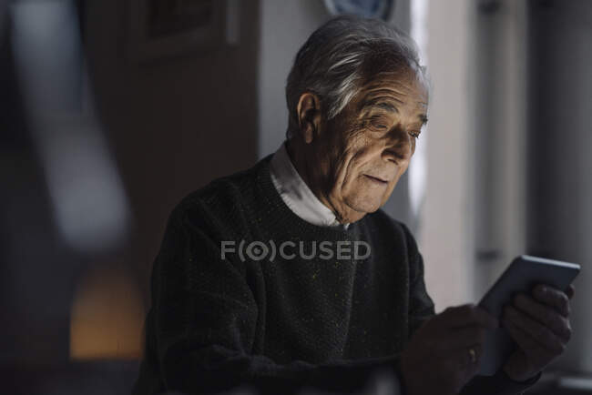 Hombre mayor usando tableta en casa - foto de stock