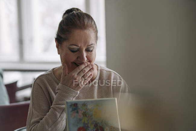 Heureuse femme âgée regardant dans la boîte à bijoux à la maison — Photo de stock
