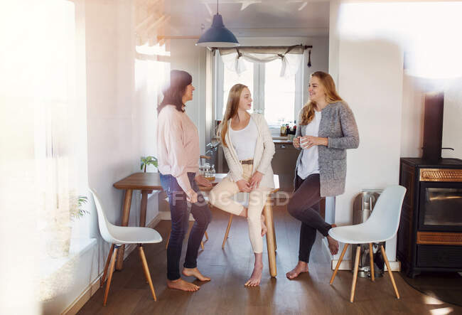 Mãe e filhas de pé na cozinha, conversando, bebendo café — Fotografia de Stock